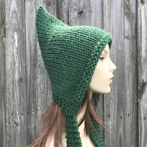 May include: A green knitted hat with a long pointed crown and two long ties. The hat is made of a soft, warm yarn and is perfect for keeping your head and ears warm in the winter.