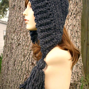 May include: A gray crocheted hooded hat with a long tassel. The hat is made of a soft, chunky yarn and has a simple, classic design.