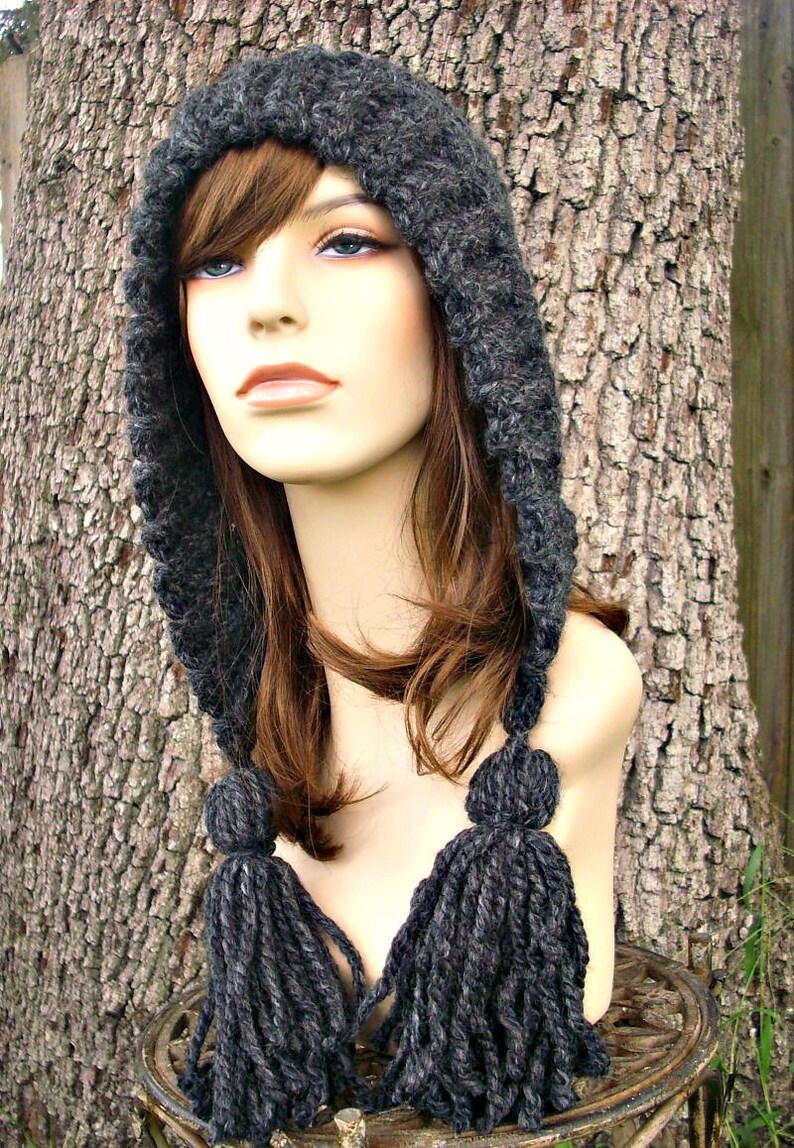 May include: A gray hooded hat with long tassels. The hat is made of a soft, fuzzy yarn and has a simple, classic design.