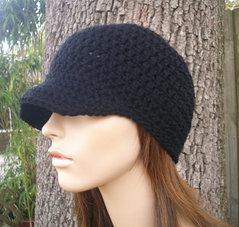 May include: A black crocheted beanie with a brim. The beanie is worn on a mannequin with long brown hair.