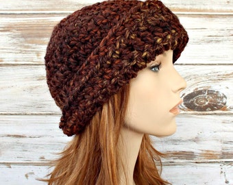 Puede incluir: Un gorro de punto slouchy de color marrón y dorado con un borde doblado.