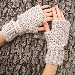 May include: A pair of beige crocheted fingerless gloves with brown button accents.