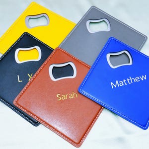 Peut inclure: Ensemble de dessous de verre ouvre-bouteilles personnalisés de différentes couleurs : jaune, gris, bleu, marron et noir. Chaque dessous de verre est équipé d'un ouvre-bouteille intégré et personnalisé avec un nom ou des initiales dorées.