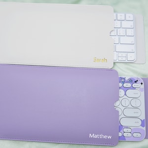 Può includere: Due custodie per tastiera, una bianca e una lavanda, ciascuna con una tastiera all'interno. La custodia bianca ha il nome "Sarah" in lettere dorate. La custodia lavanda ha il nome "Matthew" in lettere bianche.