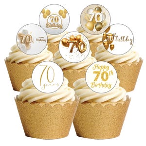 Peut inclure: Cupcakes avec glaçage blanc et caissettes dorées. Chaque cupcake est surmonté d'un cercle blanc avec du texte et des graphiques dorés célébrant un 70e anniversaire. Les motifs incluent des ballons et les mots "Happy 70th Birthday."