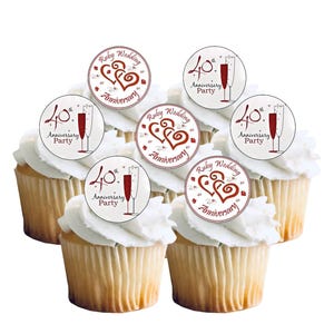 Op de afbeelding: Zes cupcakes met witte frosting, elk bekroond met een ronde decoratie. De decoraties bevatten de tekst "40e verjaardagsfeest" en "Robijnen Bruiloft Jubileum", samen met afbeeldingen van champagneglazen en harten.