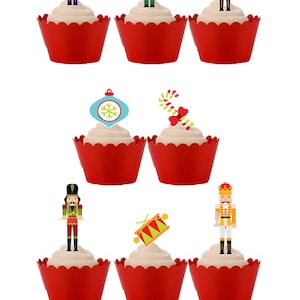 May include: Nine cupcakes with white icing in red cases. Each cupcake is decorated with a festive Christmas topper, including nutcrackers, an ornament, and a candy cane.