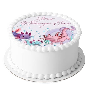Op de afbeelding: Een ronde witte taart versierd met een rand van botercrème. De bovenkant van de taart heeft een kleurrijke illustratie van axolotls en de tekst "Your Message Here". De axolotls zijn in tinten roze, paars en blauw.