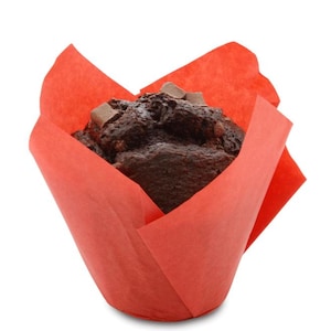 Könnte beinhalten: Ein dunkelbrauner Schokoladenmuffin mit sichtbaren Schokoladenstückchen, der in einer leuchtend roten Tulpen-Muffinform aus Papier steckt. Das Gebäck hat eine texturierte, poröse Oberfläche und ist vor einem weißen Hintergrund abgebildet.