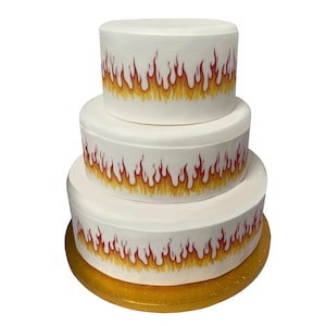 May include: A three-tiered white cake decorated with a red and yellow flame design. The cake is on a gold cake board.