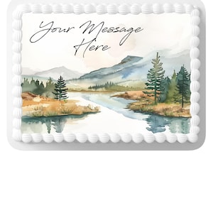 Peut inclure: Gâteau rectangulaire avec un paysage à l'aquarelle. L'image présente un lac, des montagnes et des arbres, avec le texte "Your Message Here" en écriture cursive. Le gâteau est bordé de glaçage blanc.