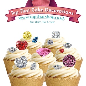 May include: Cupcakes with white icing and jewel-shaped decorations. The cupcakes are in gold-coloured paper cases. The jewels are in various colours, including yellow, blue, red, pink, and clear. The text "Top That Cake Decorations" is displayed.