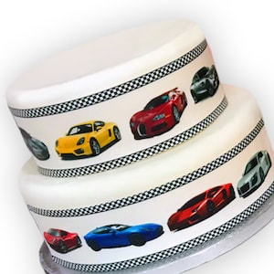 May include: A two-tiered white cake decorated with images of sports cars and a black and white chequered border. The cake features cars in red, yellow, and blue.