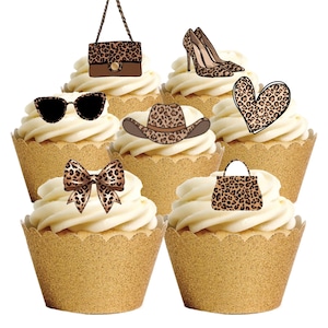 May include: Six cupcakes with white icing and gold cupcake cases. Each is topped with a leopard print accessory: sunglasses, a handbag, high heels, a cowboy hat, a bow, and a heart.