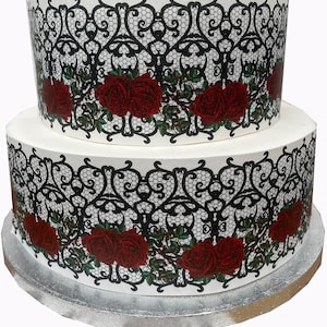 Peut inclure: Gâteau blanc à deux étages décoré de dentelle noire et de roses rouges. Le gâteau est sur un plateau à gâteau argenté.