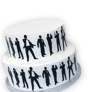 Peut inclure: Un gâteau blanc à deux étages décoré de silhouettes noires d'hommes en costume tenant des armes à feu. Le gâteau est sur un support à gâteau argenté.