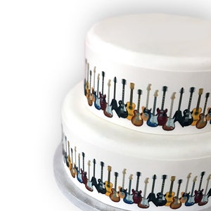 May include: A two-tiered white cake featuring a repeating border of colourful guitars. The guitars are in various colours and styles, creating a musical theme. The cake sits on a silver cake board, ideal for a music-themed celebration.