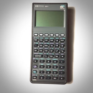 May include: A black Hewlett Packard 48G+ graphing calculator with a gray screen and a silver keypad. The calculator has a variety of buttons, including trigonometric functions, matrix operations, and programming functions.