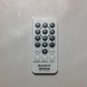 May include: White remote control for a Sony clock radio with buttons for audio in, radio band, mode, tune, off, preset, volume, menu, enter, mega bass, mega xpand, and snooze. The remote has the text "SONY CLOCK RADIO RMT-CCS10iP" printed on it.