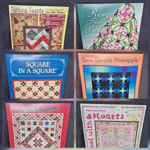 May include: A collection of six instructional quilting books featuring titles such as Turning Twenty, Rings That Bind, Square in a Square, Sew Simple Pineapple, Monterrey Medallions, and Hearts, each displaying colorful quilt patterns on the covers.