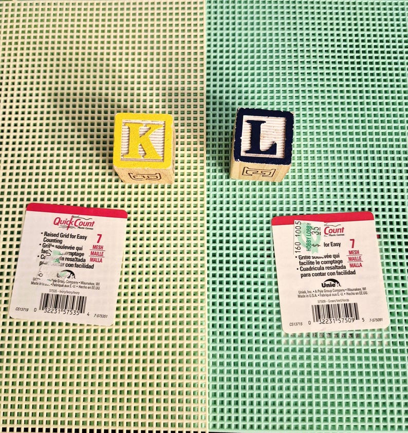 May include: Two square wooden alphabet blocks, one yellow with the letter K and one dark blue with the letter L, placed on two plastic mesh sheets, one ivory and one mint green, each featuring a Quick Count label with a barcode and text.