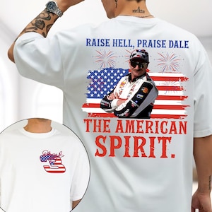 May include: A white t-shirt featuring a graphic on the back of a race car driver wearing sunglasses in front of an American flag with fireworks and the text RAISE HELL, PRAISE DALE THE AMERICAN SPIRIT. The front chest has a number 3 with a flag pattern.