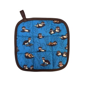May include: Square blue pot holder with a brown border and hanging loop. The pot holder features a repeating pattern of otters in various poses against a background of stylized seaweed. The otters are in shades of brown, black, and white.