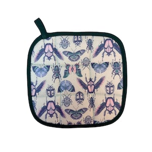 May include: A square quilted pot holder with a light cream background featuring a repeating pattern of various beetles and butterflies in shades of purple, blue, and pink. The item has a dark green fabric border and a small hanging loop at the top.