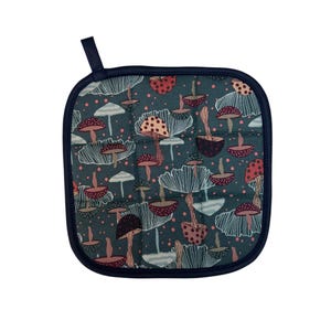 May include: A square teal blue pot holder with a quilted texture and a dark blue trim. The pot holder features a repeating pattern of stylized mushrooms in shades of red, pink, brown, and white.