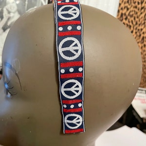 Faixa de cabeça em sarja com símbolo da paz azul/vermelho/branco dos anos 60