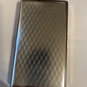 May include: A silver cigarette case with a geometric pattern.