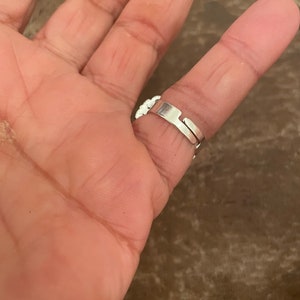 Puede incluir: Un anillo ajustable de plata con un dise&ntilde;o floral. El anillo se lleva en un dedo.