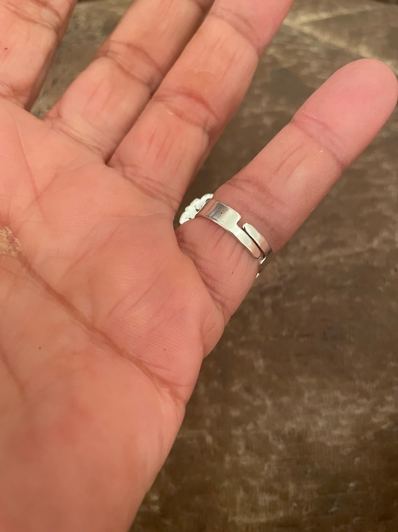 Puede incluir: Un anillo ajustable de plata con un dise&ntilde;o floral. El anillo se lleva en un dedo.