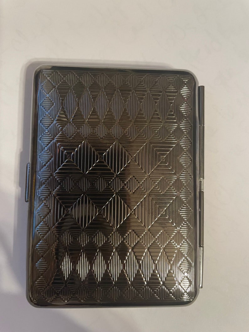 May include: A silver cigarette case with a geometric pattern.