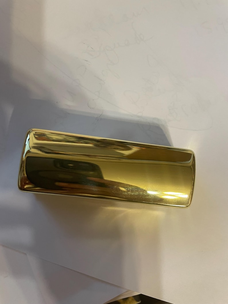 May include: A gold-colored rectangular box with a smooth, shiny surface.