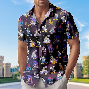 Könnte beinhalten: Schwarzes Hemd mit Knöpfen und einem Design zum 70. Jubiläum von Disneyland. Das Muster zeigt Disney-Figuren, Schlösser und die Zahl 70 in Lila und Weiß auf dunklem Hintergrund.