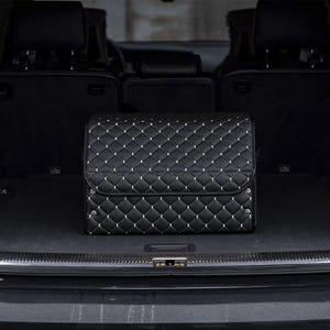 May include: Black quilted storage box in the trunk of a car. The box has a diamond pattern and is made of a durable material.
