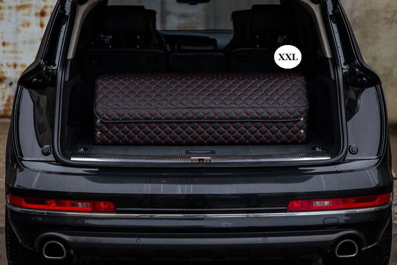 May include: A black quilted car trunk liner with red stitching. The liner is labeled "XXL".