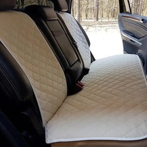 May include: Beige quilted car seat covers. The covers are diamond-stitched and designed to fit the back seats of a vehicle. The seats are installed in a black interior, with a door open in the background.