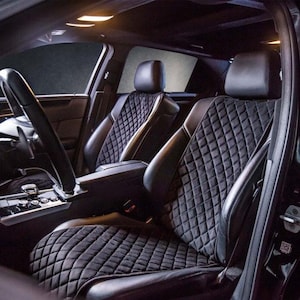 May include: Black quilted car seat covers with diamond stitching. The covers are installed in the front seats of a car.