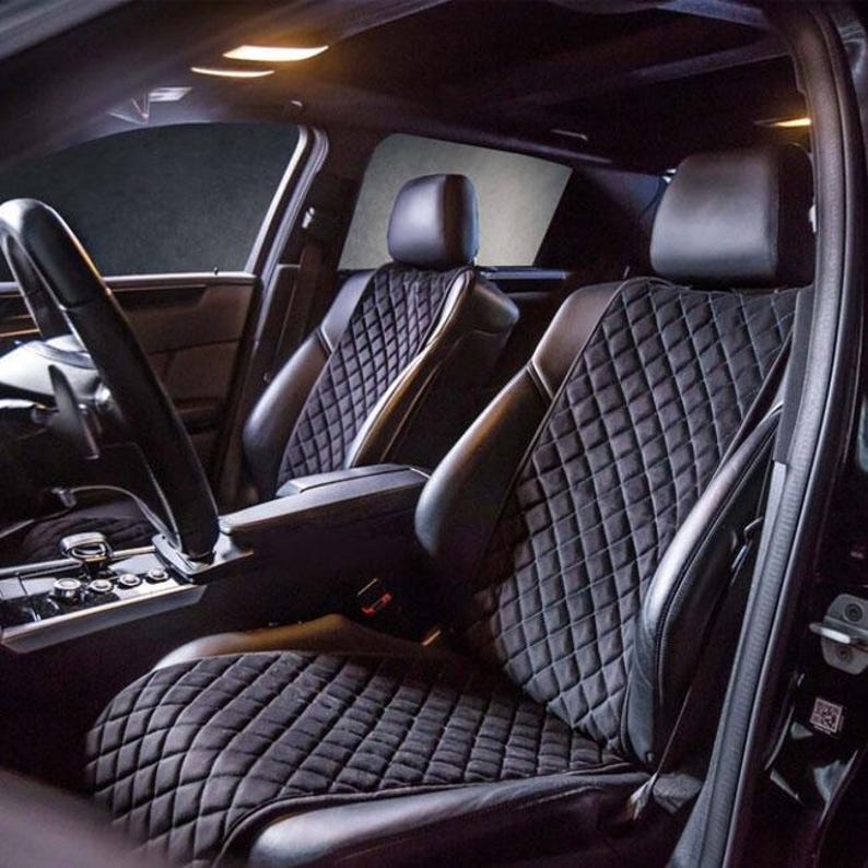 May include: Black quilted car seat covers with diamond stitching. The covers are installed in the front seats of a car.