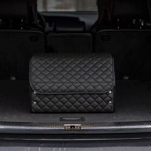 May include: Black quilted car trunk organizer with a diamond pattern. The organizer is in the back of a black SUV.