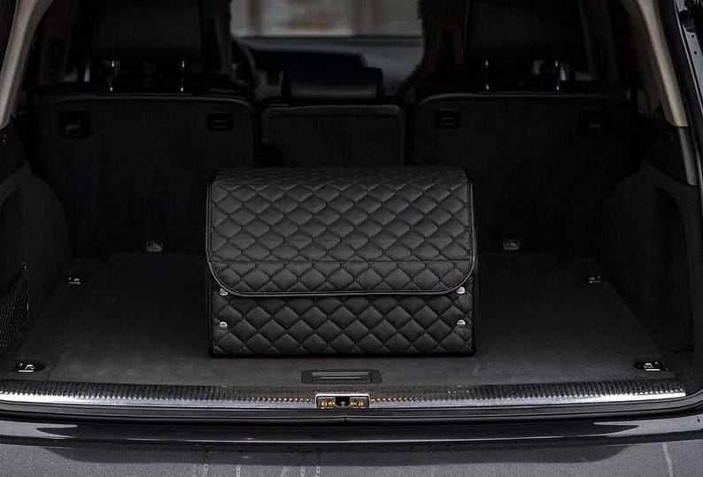 May include: Black quilted car trunk organizer with a diamond pattern. The organizer is in the back of a black SUV.