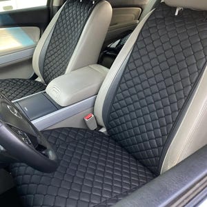 Könnte beinhalten: Schwarze gesteppte Autositzbezüge mit Rautenmuster. Die Bezüge sind in den Vordersitzen eines Autos installiert.