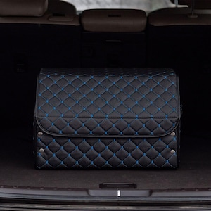 May include: Black quilted storage organizer with blue stitching in the trunk of a car.
