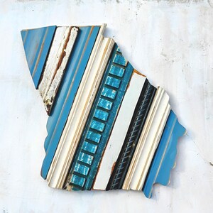 May include: A blue, white, and black wood wall art piece in the shape of the state of South Carolina. The wood is arranged in a diagonal pattern.