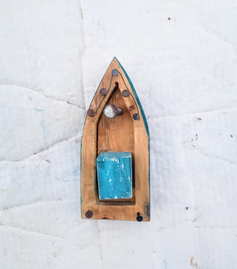 Pu&ograve; includere: Una barca giocattolo di legno con uno scafo blu-verde e un ponte in legno. La barca ha un piccolo blocco di legno all'interno ed &egrave; decorata con chiodi di metallo.