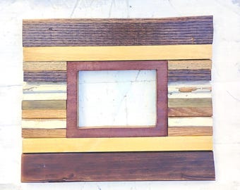 May include: A rectangular wooden picture frame with a central opening. The frame is constructed from various wood pieces in shades of brown, yellow, and cream. The inner frame is a deep reddish-brown color.