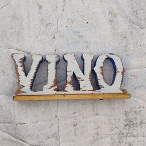 May include: White wooden letters spelling "VINO" with blue trim, mounted on a wooden base.