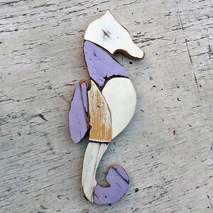 May include: A purple, white, and beige wooden seahorse sculpture. The seahorse is made of reclaimed wood and has a rustic, distressed look.